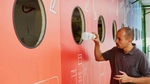 Un homme dépose une bouteille en plastique dans un grand mur de recyclage coloré.